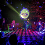 a stage with musicians, a screen with lips