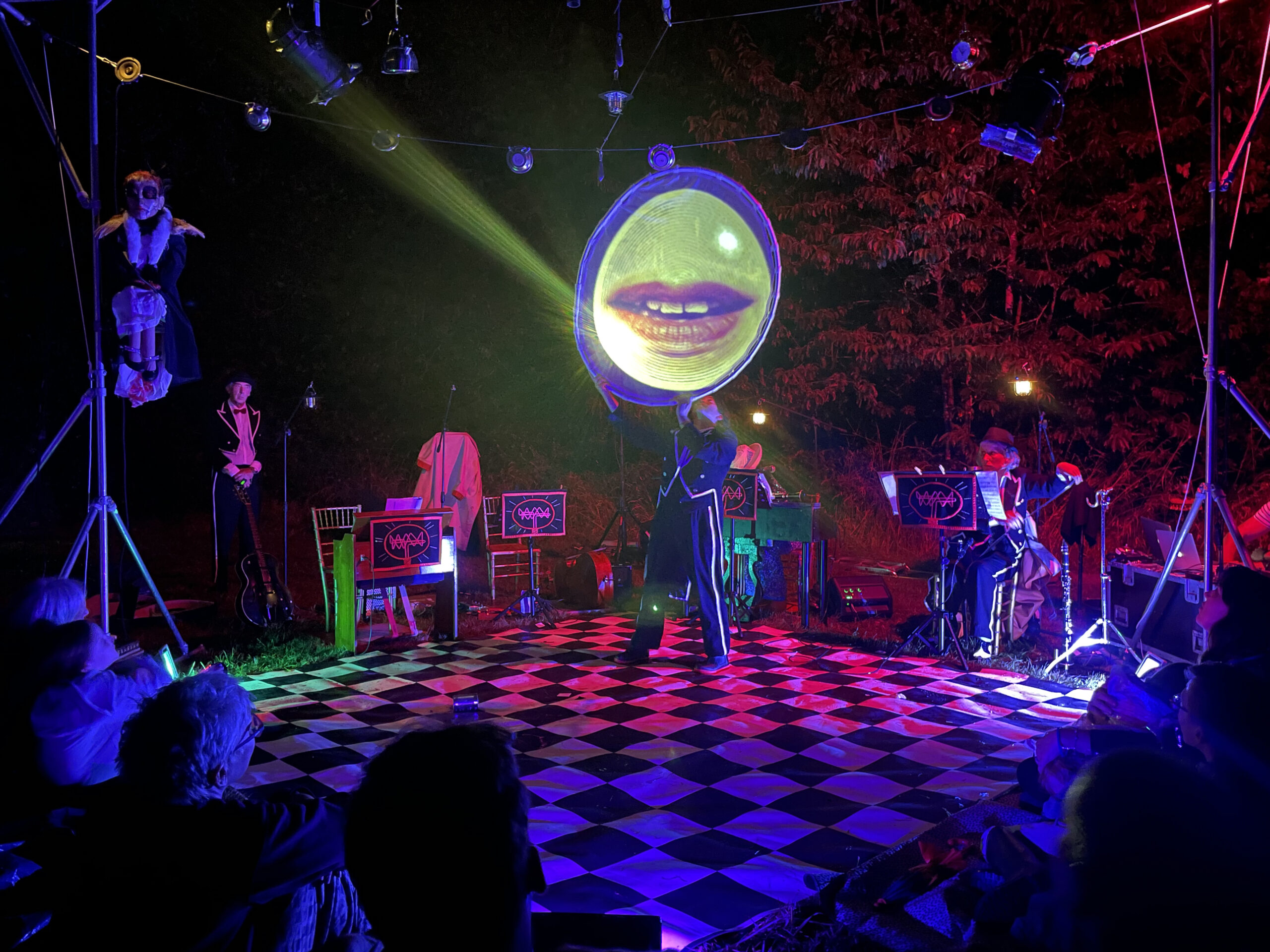 a stage with musicians, a screen with lips