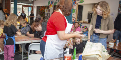 A studio volunteer offering support to a community member, assisting with creative skills.